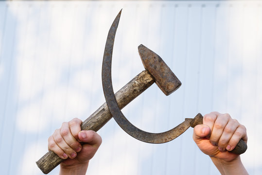 Male hands holding sickle and hammer