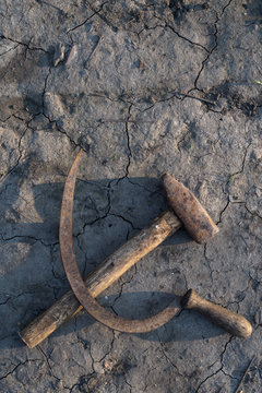 Sickle and hammer crossed on the cracked soil