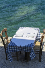 Table and two chairs of street greece restaurant on Crete in the sunny day near the sea