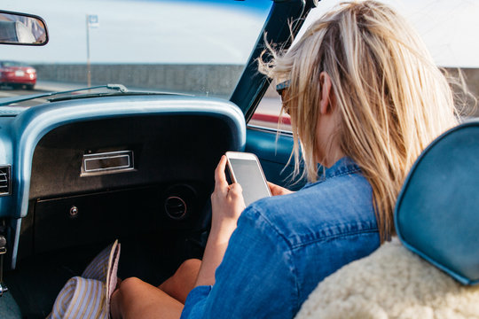 young female on mobile cell phone while riding in convertible car