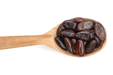 cocoa bean in a wooden spoon isolated on white background close-up top view