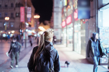 Back view of girl walking on city street at night, Prague