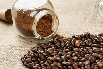 Roasted coffee beans and glass jar with ground coffee inside