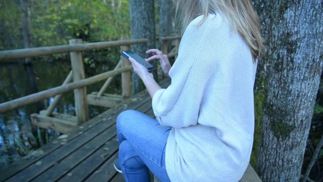 Woman in the wild forest with smart phone