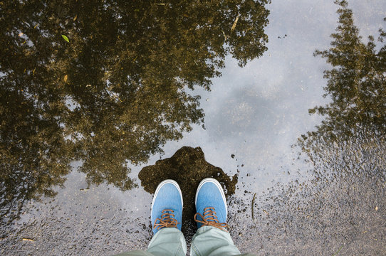 Puddle with tree refelction, blue sneakers, footsie, personal perspective