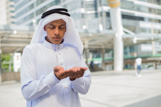 Muslim man praying in public place and modern building background