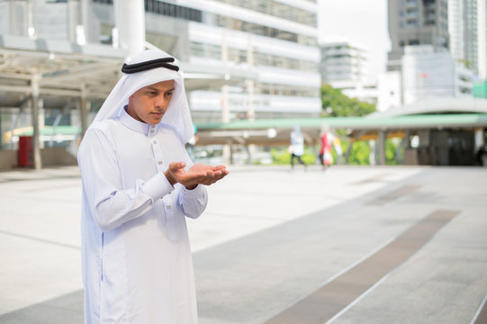 Muslim man praying in public place and modern building background