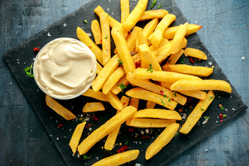 Homemade Baked Potato Fries with Mayonnaise, salt, pepper on black stone board
