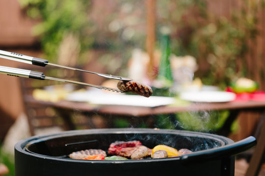 Meat and vegetables being grilled on a charcoal barbecue outdoors