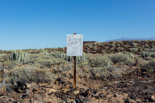 Signboard in the middle of a natural area with bushes and cactus