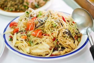 Som Tum Thai (Green Papaya Salad) with salted crab and tomato serve on white plate at Pattaya Thailand for food homemade background or texture.