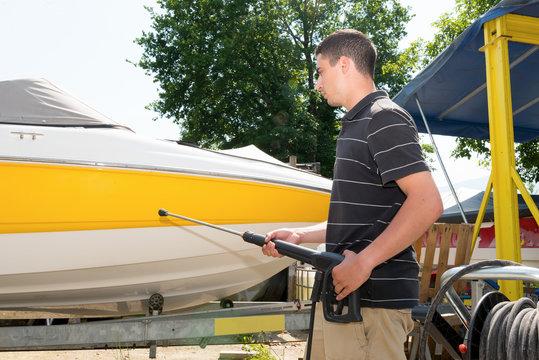 Young Man Cleaning Boat With High Pressure Water