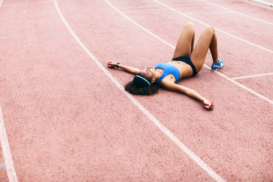 Tired african american female sprinter lying on a track.