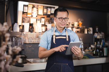 Asian man barista smiling with tablet in her hand,Female employees are taking orders from online...