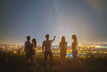 The five friends stand on the background of the city. evening night time