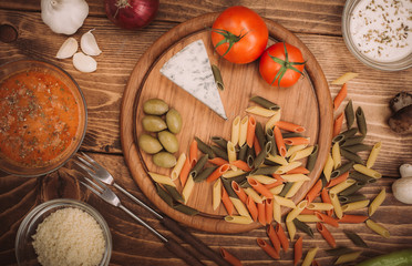 Food ingredients for preparing pasta on wooden kitchen board