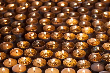Burning tea light candle flames. Lighted tealight candles spread on a garden table.