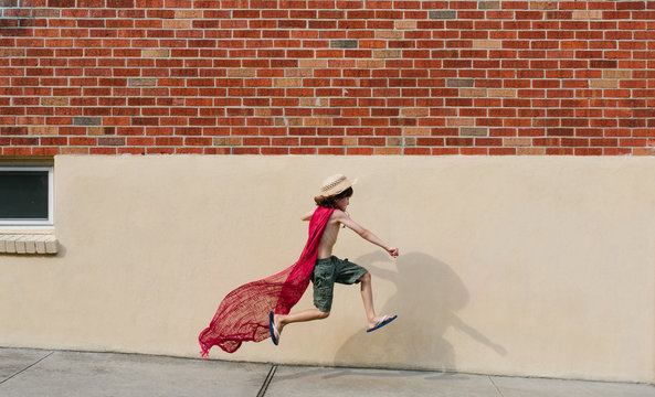 Young boy in homemade cape jumps into the air
