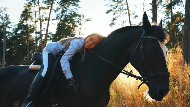 beautiful girl riding on a horse hugging her and stroking