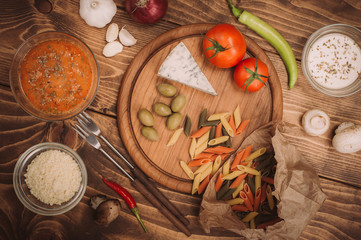 Food ingredients for preparing pasta on wooden kitchen board