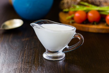 Natural cream dip in a glass bowl on dark wooden board.