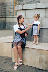 little girl with her mother in the identical dresses with candy on a background of gray buildings and arches