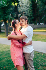 young loving couple in the park outdoors against the trees