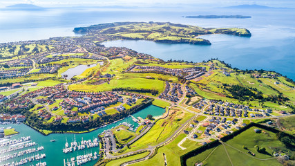 Aerial view on residential suburbs surrounded by sunny ocean harbour. Whangaparoa peninsula, Auckland, New Zealand - obrazy, fototapety, plakaty