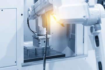 The  robot in modern CNC machine operation.The modern CNC manufacturing process using autonomous robot for setting work piece.