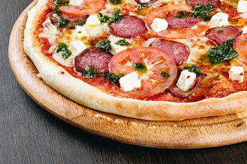 Delicious Italian pizza pepperoni with tomato, cheese and sausage close up on wood background 