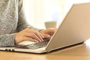 Woman hands typing in a laptop keyboard on a desk