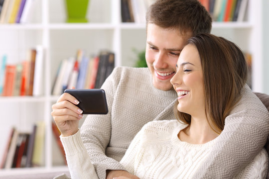 Couple watching on line content in a smart phone at home