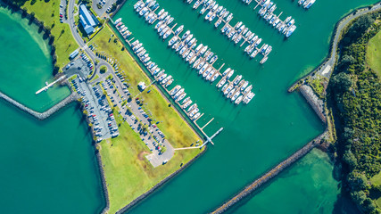 Aerial view on the entrance to the marina with boats resting along the pier and cars waiting on the parking space. Auckland, New Zealand