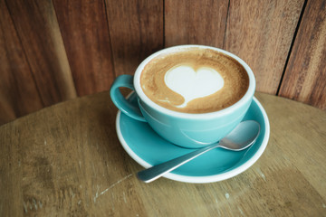 cup with coffee has a heart shape on top placed on wooden table and wood wall are background. image for coffee art, beverage, drink, food, art concept
