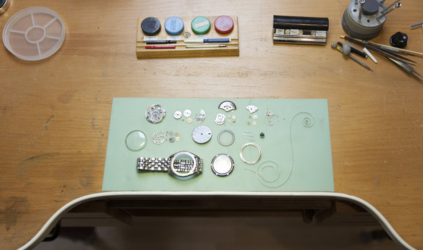 Parts of deconstructed watch lying on clockmaker table