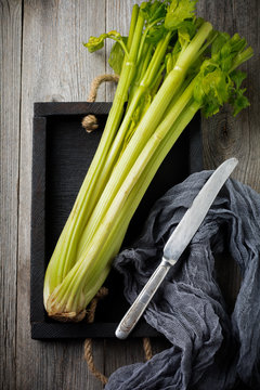 Bouquet of fresh celery in vintage box on an old wooden background. Selective focus. Top view. Copy space.
