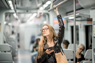 Lifestyle portrait of a young businesswoman standing with smart phone at the modern train