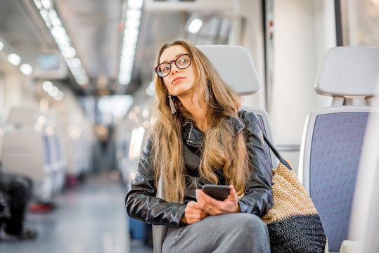 Lifestyle portrait of a young businesswoman sitting with smart phone at the modern train