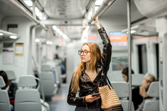 Lifestyle portrait of a young businesswoman standing with smart phone at the modern train
