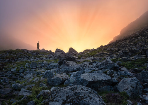 Man standing fornt of sunlight at summer evening in mountain Lofoten Island