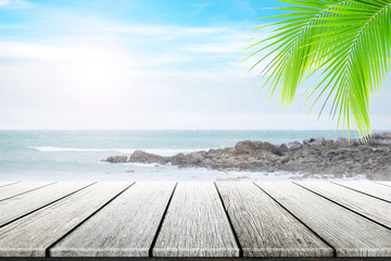 Empty wooden table and coconut leaves with party on beach blurred background in summer time.