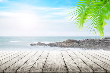 Fototapeta premium Empty wooden table and coconut leaves with party on beach blurred background in summer time.