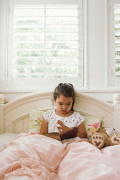Young cute girl reading in bed for homeschool