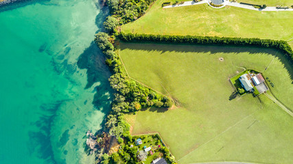Aerial view on a farmland on the shore of sunny harbour. Whangaparoa peninsula, Auckland, New Zealand