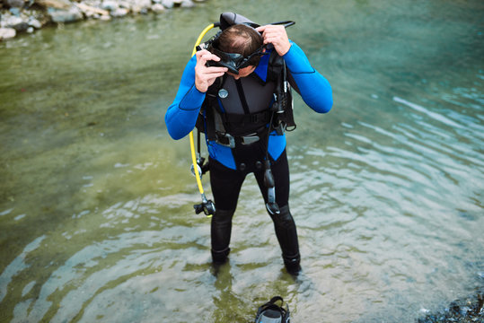 Male diver in wetsuit checking equipments before immerse