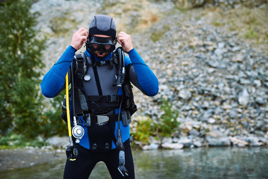 Male diver in wetsuit checking equipments before immerse