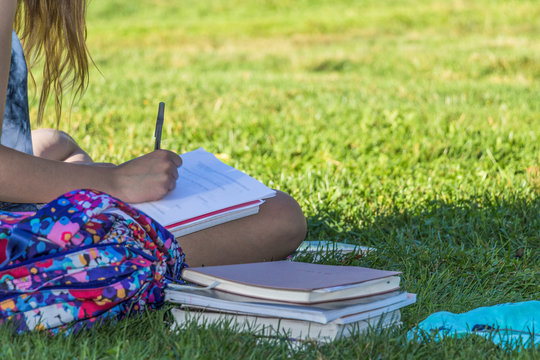 Hand of a young woman is studying outdoor on grass