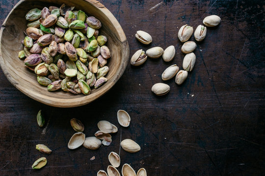 Pistachio nuts in a wooden bowl from above