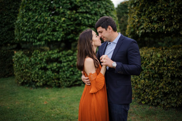 Tender love story of beautiful woman in orange dress and man in stylish suit