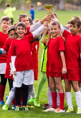 Foto op Canvas Kids soccer football - children players celebrating with a trophy after match on soccer field © Dusan Kostic